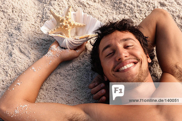 Glücklicher Mann am Strand liegend