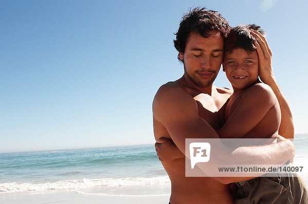 Vater umarmt Sohn am Strand