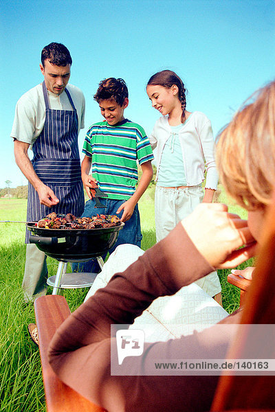 Family cooking food on barbeque