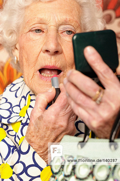 Elderly woman applying lipstick