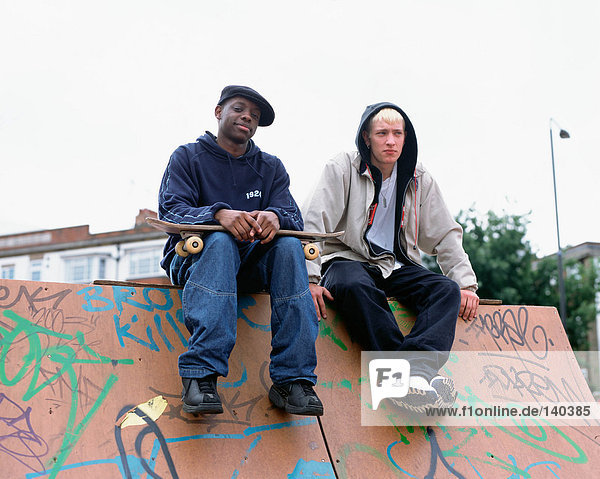 Boys sitting on skateboard ramp