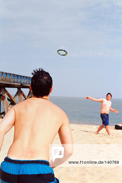 Jungs beim Frisbee spielen am Strand