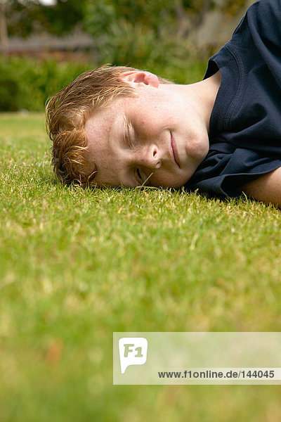 Lächelnder Junge auf dem Gras liegend