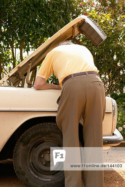 Rückansicht eines älteren Mannes beim Reparieren eines Autos