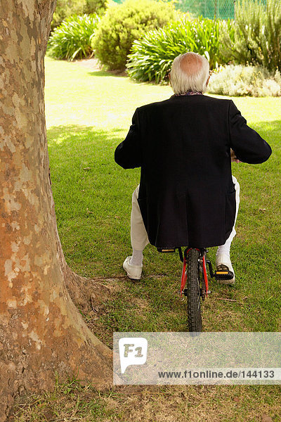 Ein älterer Mann  der auf einem Fahrrad sitzt.