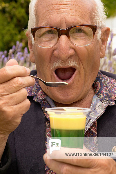 Ein älterer Mann,  der ein Dessert isst.