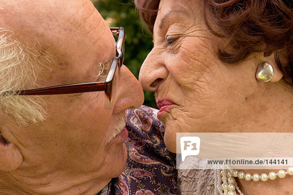 Ein älteres Paar,  das sich küssen will.