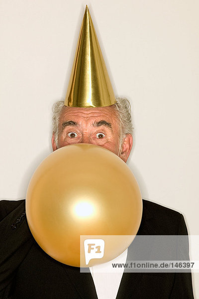 Senior Mann beim Aufblasen eines Ballons