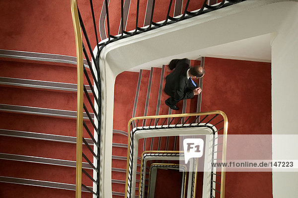 Businessman walking up spiral stairway