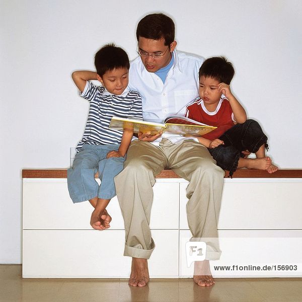 Vater beim Lesen mit Söhnen