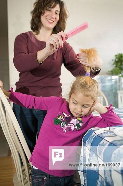 Mutter kämmt das Haar der Tochter