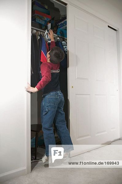 Junge versucht Regal im Schrank zu erreichen