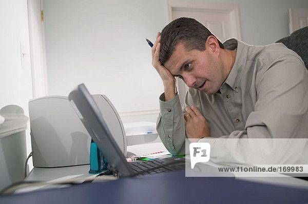 Man looking frustrated at his laptop computer
