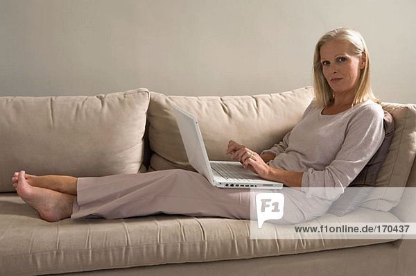 Frau auf Sofa mit Laptop-Computer