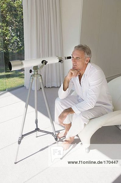 Mature man looking through telescope