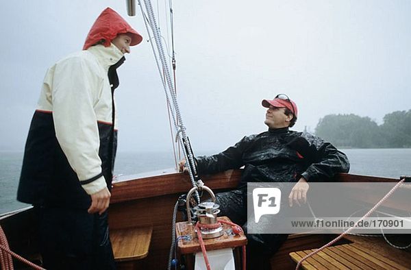 Two men on a boat in the rain