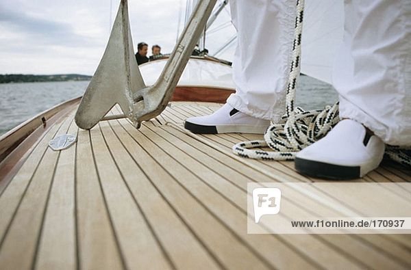 Close-up of feet and anchor on deck of boat