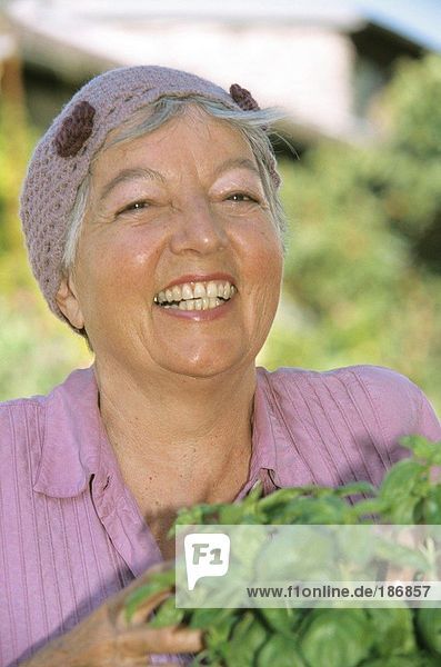Lächelnde Seniorin mit Basilikumpflanzen  Nahaufnahme