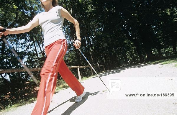 Frau beim Wandern mit Stöcken  Nordic Walking