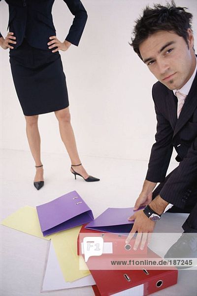 Man picking up folders for woman