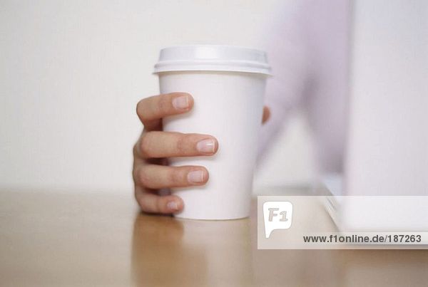 Frau hält eine Kaffeetasse aus Papier in der Hand