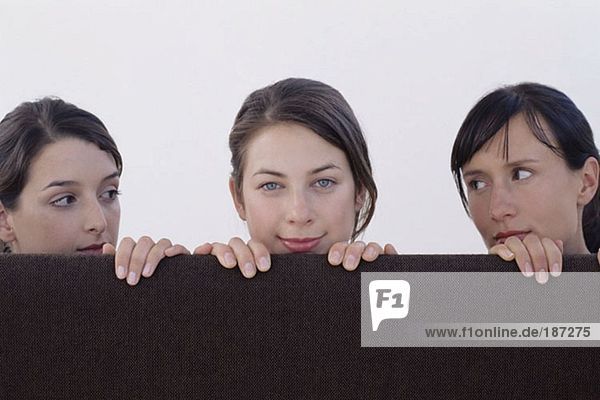 Three women looking over cubicle
