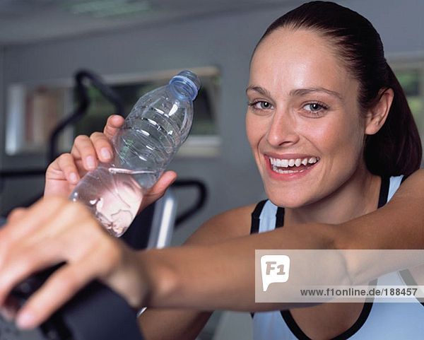 Frau trinkt Wasser in einer Turnhalle