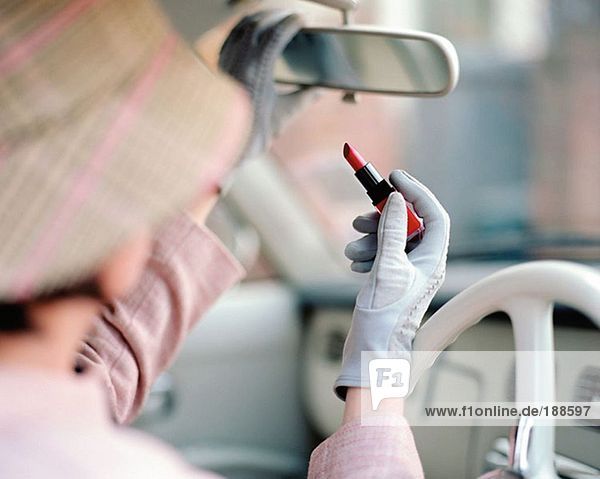 Frau beim Auftragen von Lippenstift im Auto