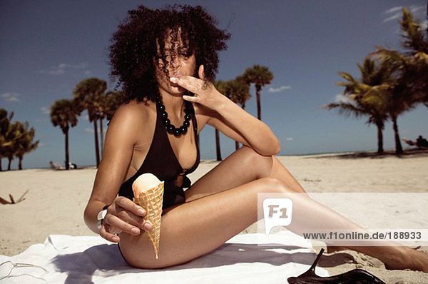 Frau isst ein Eis am Strand.
