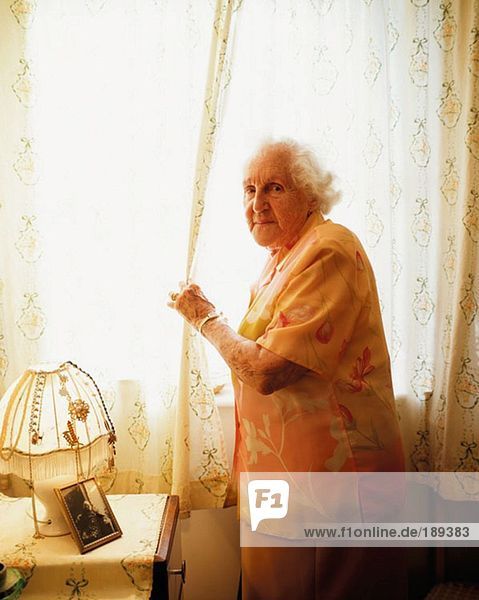Elderly woman opening curtain
