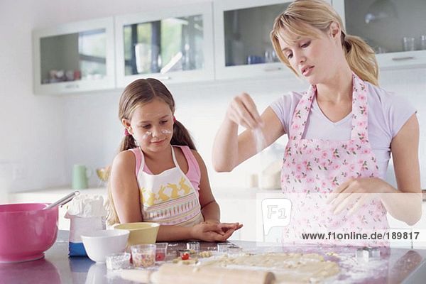 Mädchen hilft Mutter beim Kekse backen
