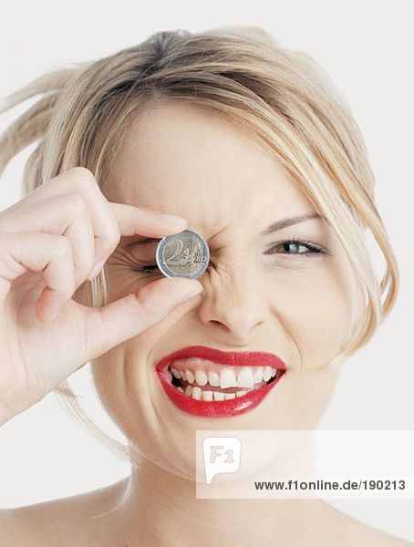 Frau hält Euro-Münze am Auge
