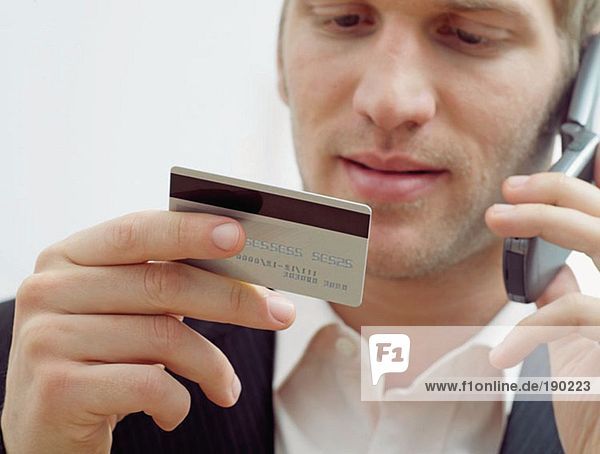 Mann auf dem Handy mit Kreditkarte