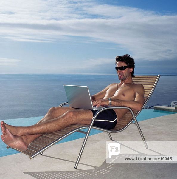 Man using laptop by the pool