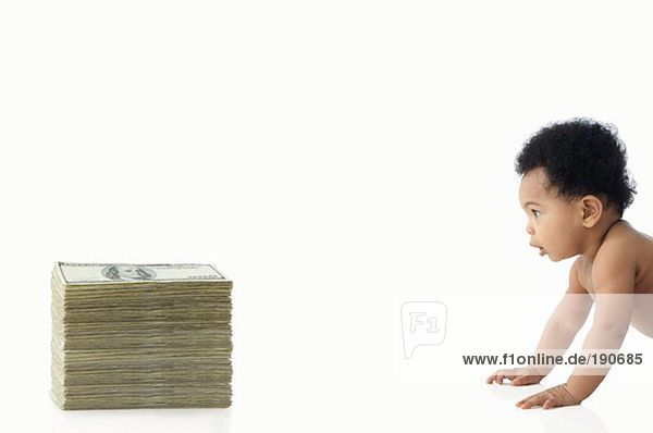 Baby krabbelt auf einen Haufen Geld zu.