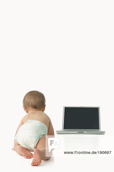 Baby krabbelt auf den Laptop zu
