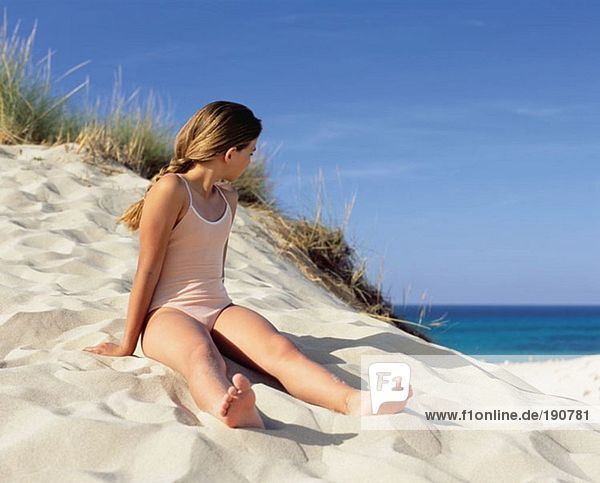 Mädchen auf einer Sanddüne sitzend