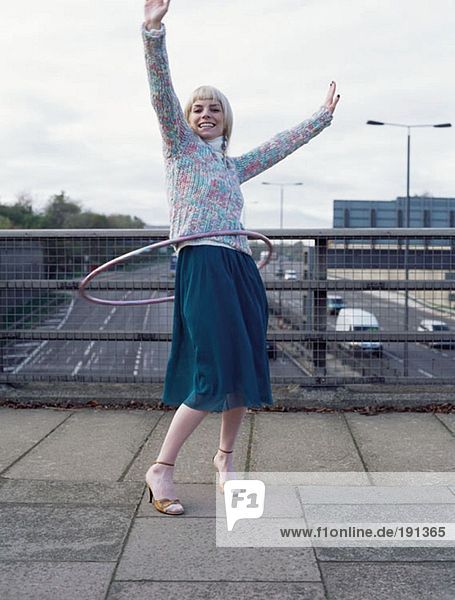 Woman playing with hula hoop on motorway bridge