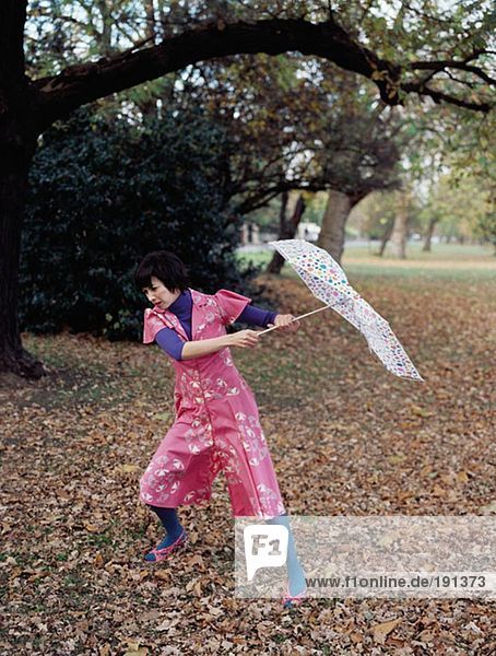 Frau mit Regenschirm kämpft gegen den Wind