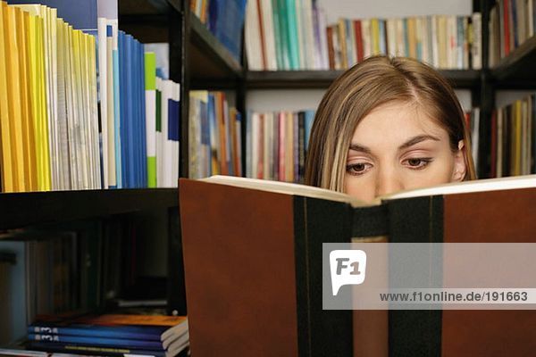 Young woman reading a book in library
