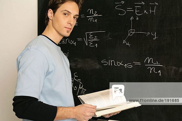 Young man standing in front of a blackboard