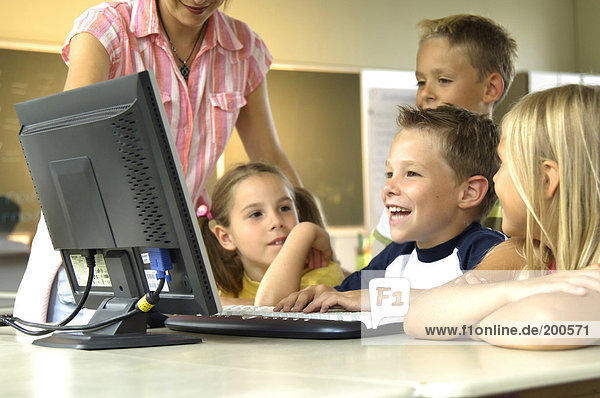 Four students and teacher looking at computer monitor