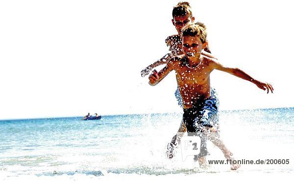 Zwei Jungs spielen im Wasser am Strand