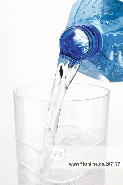 Wasser aus Plastikflasche in ein Glas giessen