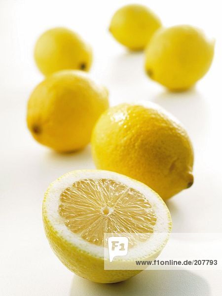 Ganze Zitronen und Zitronenhälfte