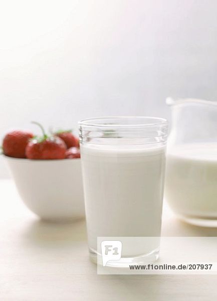 Glas Milch und Milchkrug  Erdbeeren in weisser Schale