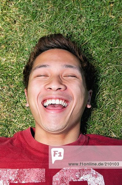 Mann auf Gras liegend und lachend