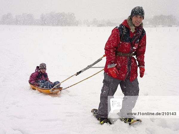 Man pulling his daughter in a sled