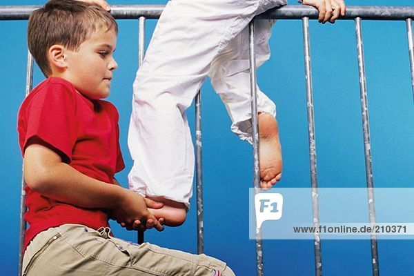 Junge hilft Freund auf ein Geländer