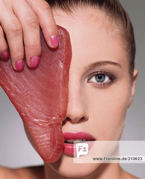 Frau hält Thunfisch-Steak über dem Auge